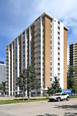 A white and brown building with a tree in front of it.