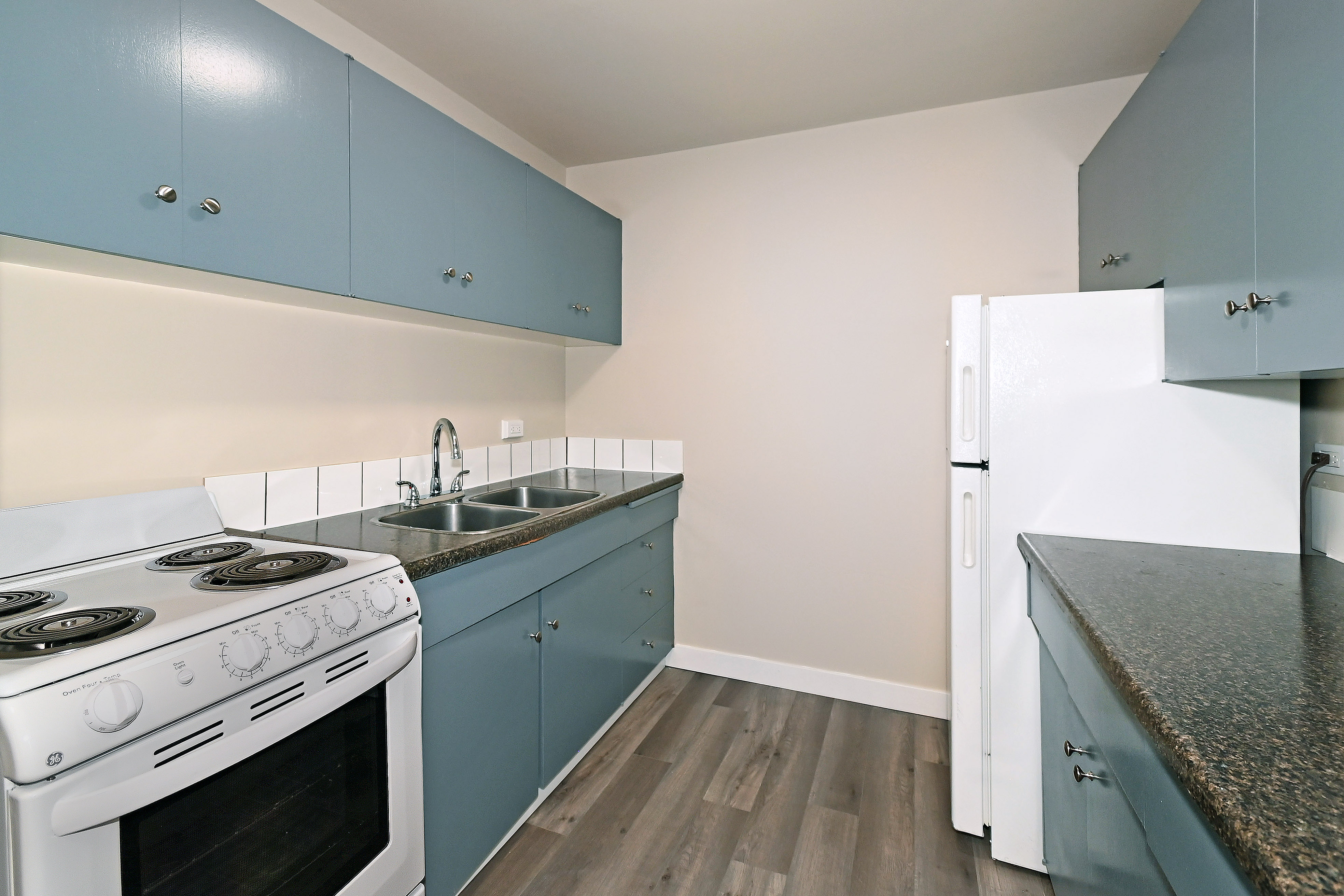 A kitchen with a white stove and blue cabinets.