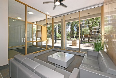 A modern living room with a glass wall and a ceiling fan.