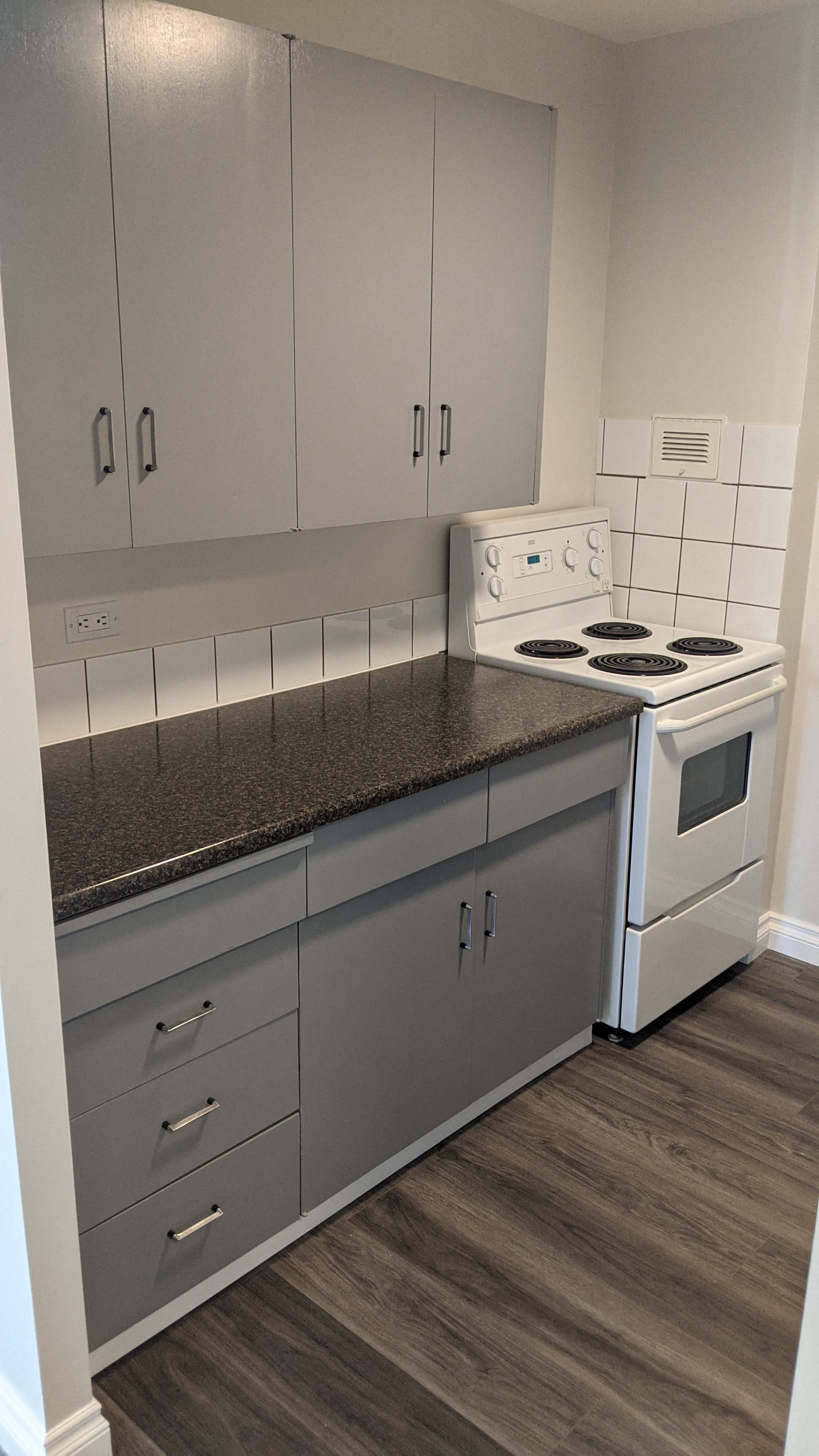a kitchen with white appliances and gray counter tops