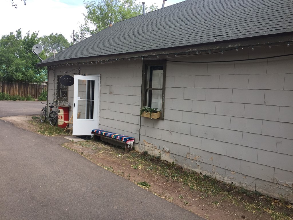 A grey building with a white door and a small window.