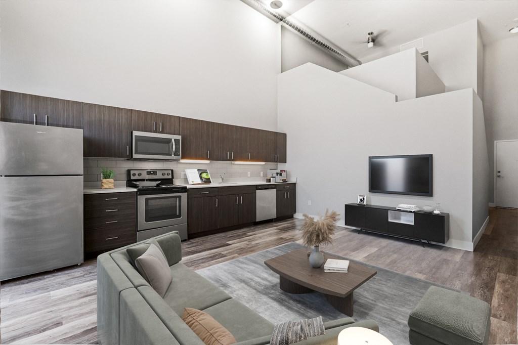 a kitchen and living room with a gray couch and a tv
