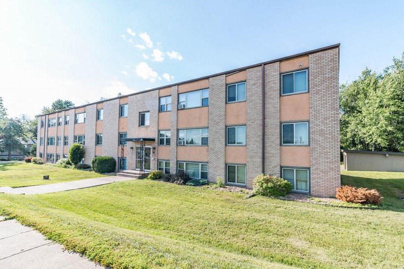 the exterior of a brick building with green grass and trees