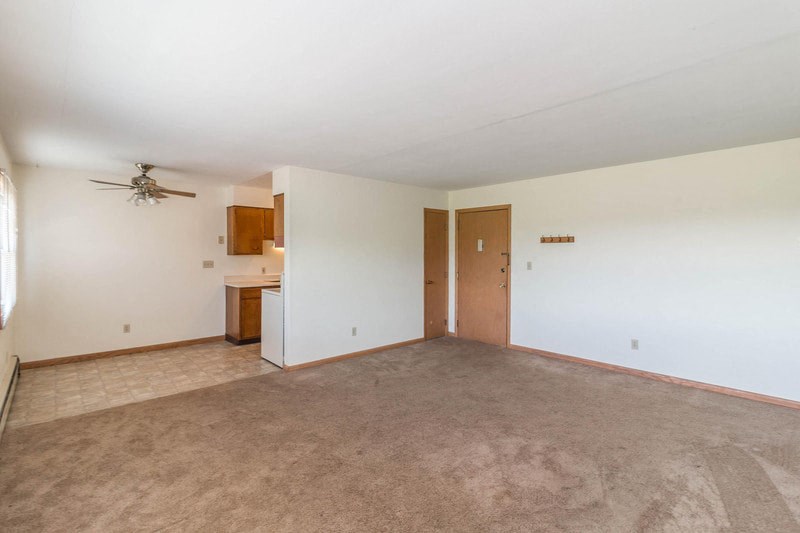 an empty living room with white walls and a ceiling fan