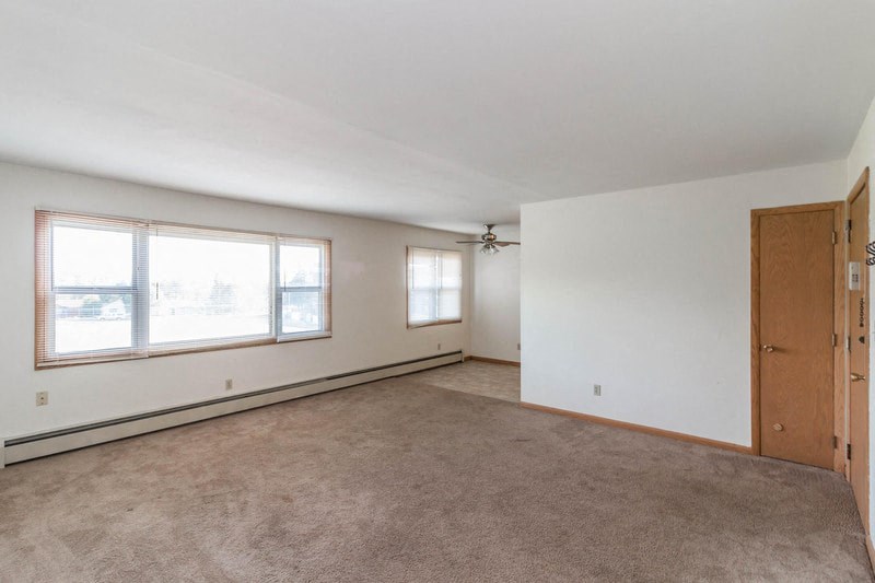 an empty living room with two windows and a door