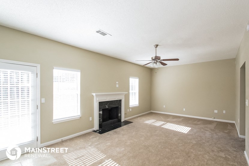 an empty living room with a fireplace and a ceiling fan