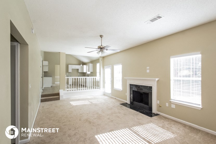an empty living room with a fireplace and a ceiling fan