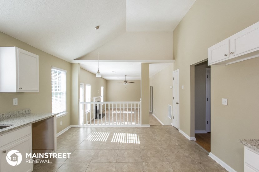 an open kitchen and living room with white cabinets and tile flooring