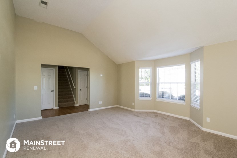 an empty living room with a staircase and windows
