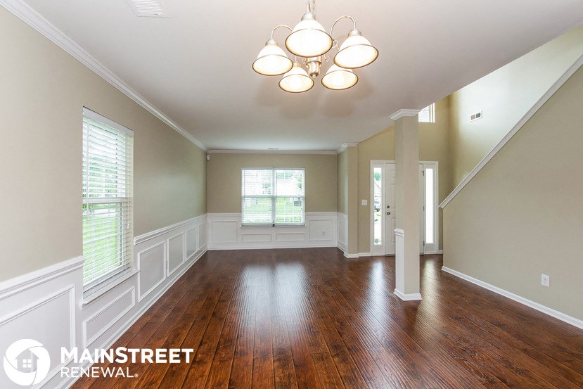 an empty living room with wood floors and a chandelier