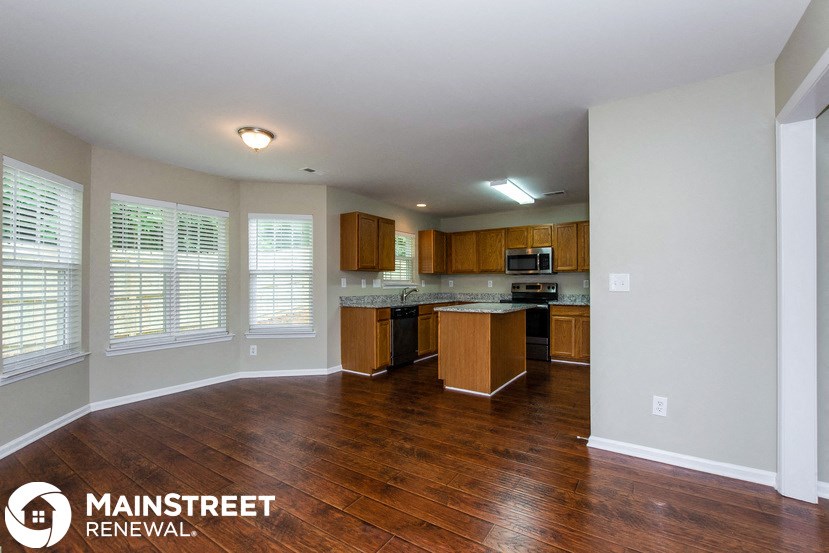 an empty kitchen with wood flooring and a large window