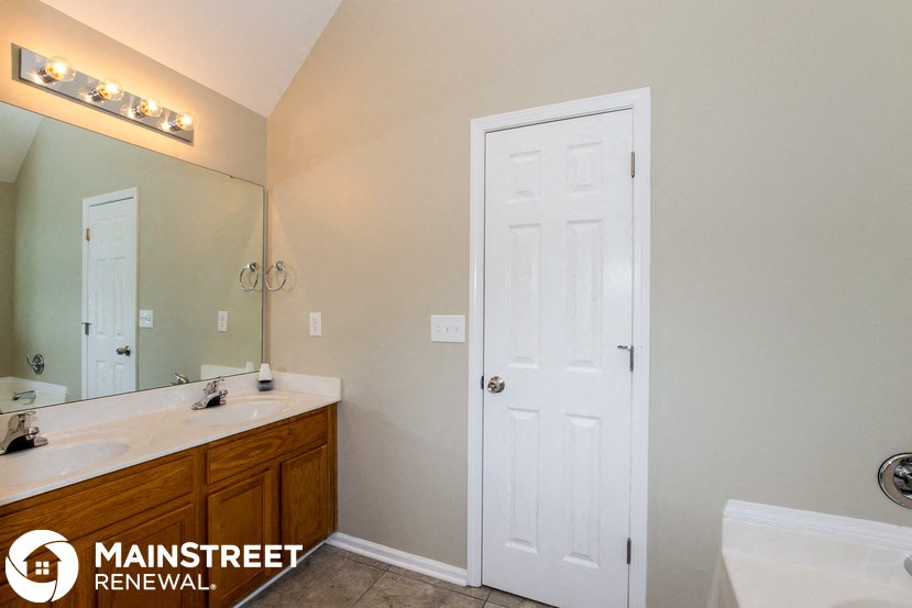 a bathroom with a white door and a sink and a mirror