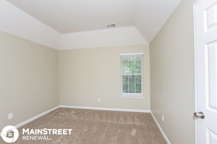 the upstairs bedroom has a carpeted floor and a window