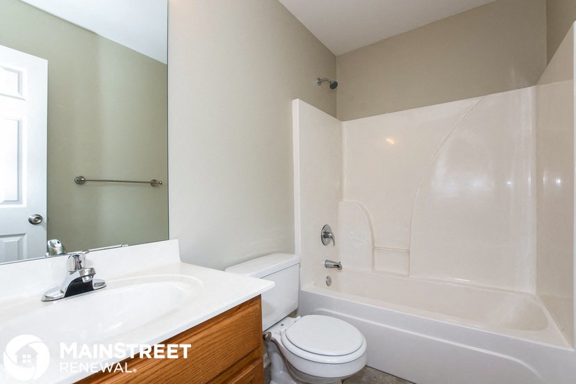 a bathroom with a toilet sink and tub and a mirror