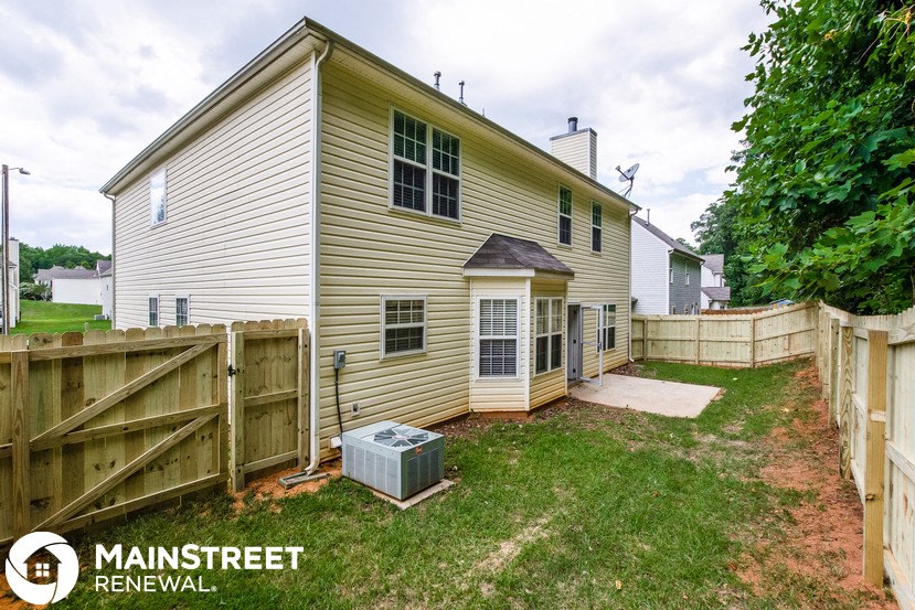 the back of a house with a fenced in yard and a wooden fence