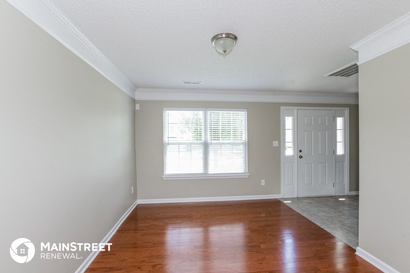 the living room of a home with wood floors and a white door