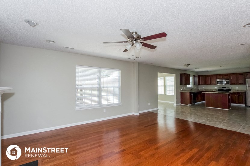 the kitchen and living room of a home with wood floors and a ceiling fan