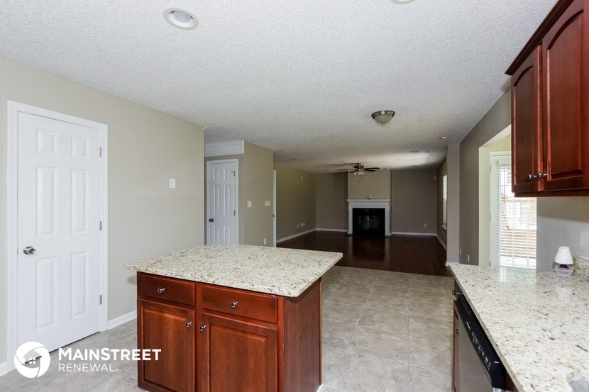 an empty kitchen with granite counter tops and a living room