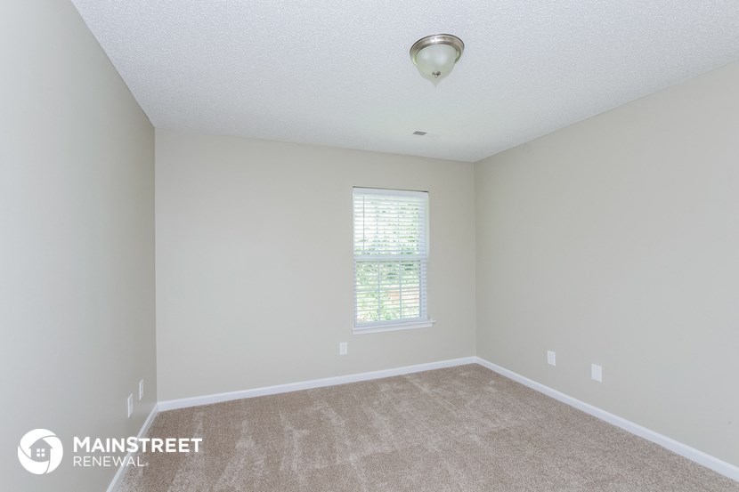 the spacious living room with carpeting and a window