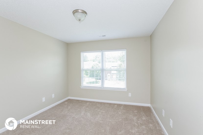 a bedroom with a large window and carpeting