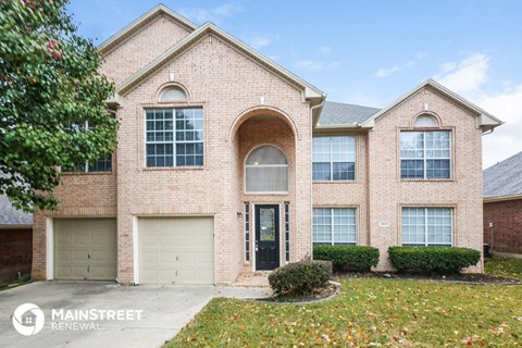 a brick house with two garage doors and a lawn