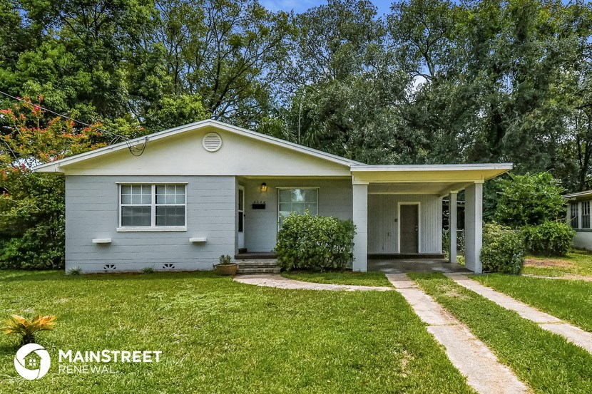 a small blue house with a lawn and trees