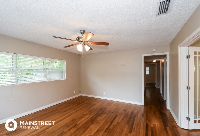 the living room and hallway of an empty house with a ceiling fan