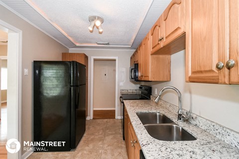 a kitchen with wood cabinets and a sink and a black refrigerator