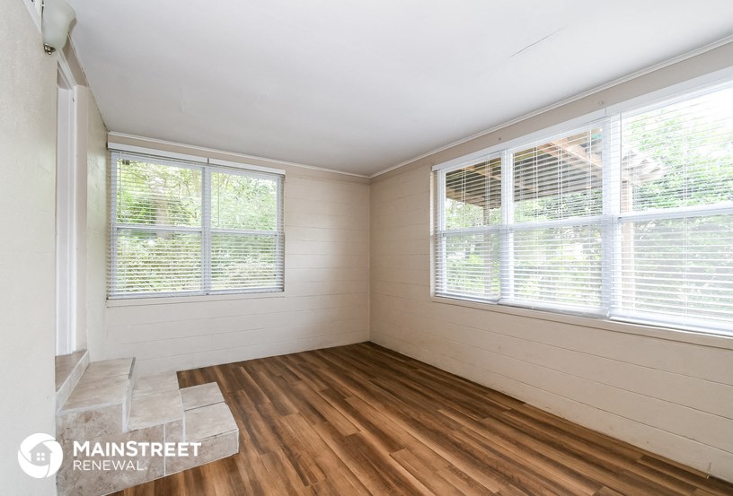 a living room with wood floors and two windows
