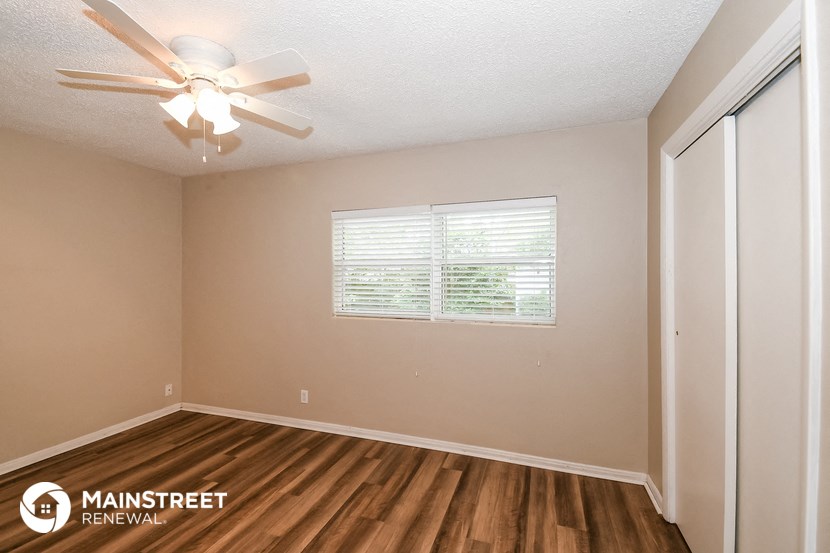 the spacious living room of this manufactured home has a ceiling fan and a window