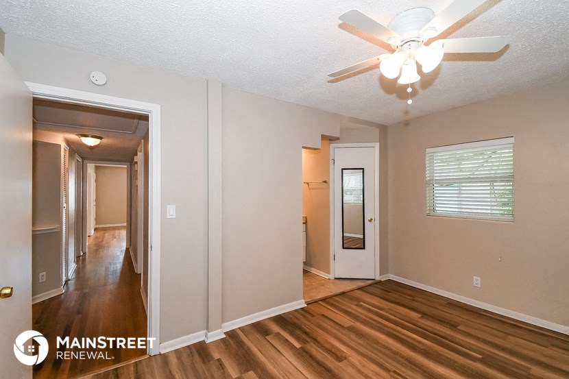 the living room and hallway of an empty house with wood floors and a ceiling fan