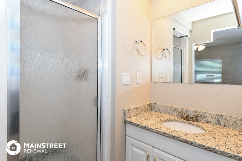 a bathroom with a sink and a shower and a mirror