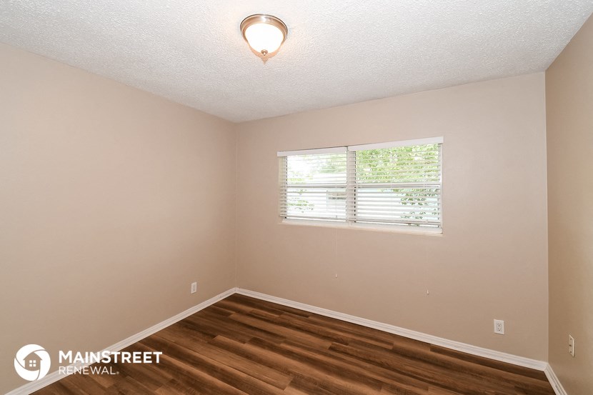 the interior of a bedroom with wood flooring and a window