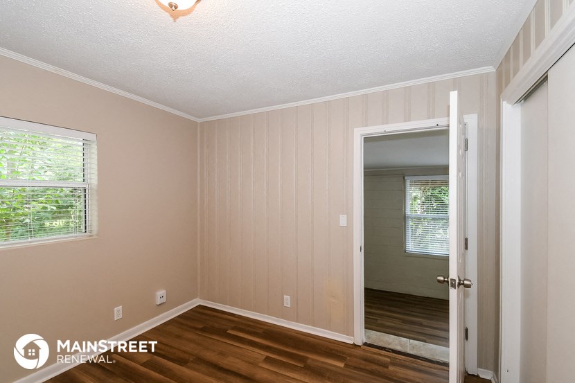 the interior of a bedroom with wood flooring and a door to the hallway