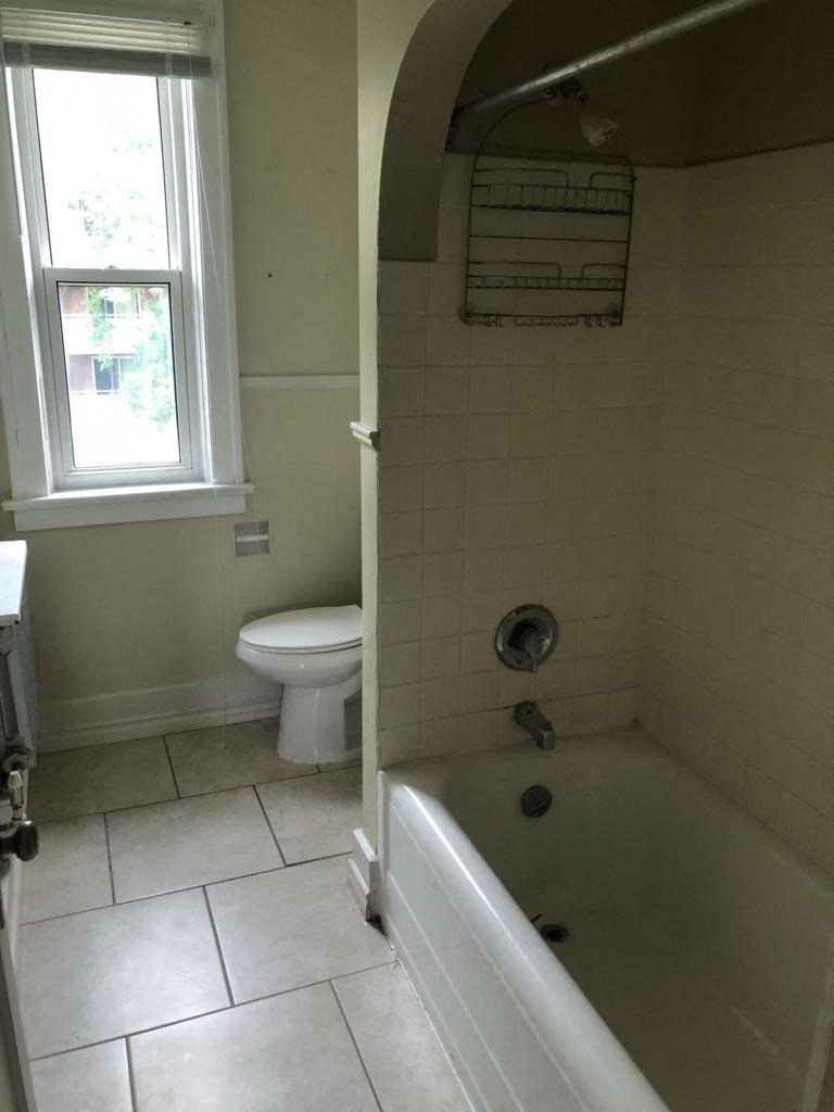 a bathroom with a tub and a toilet and a window