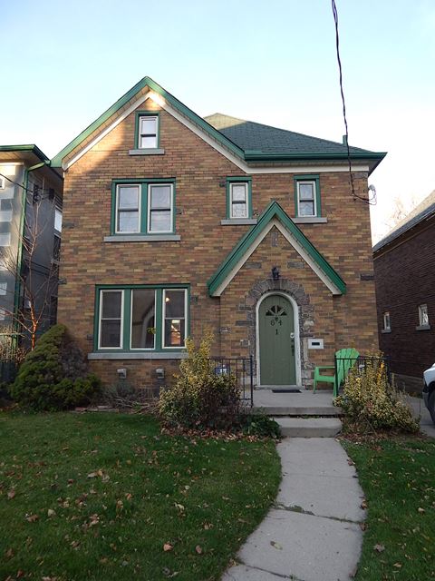 a brick house with a green door and a sidewalk