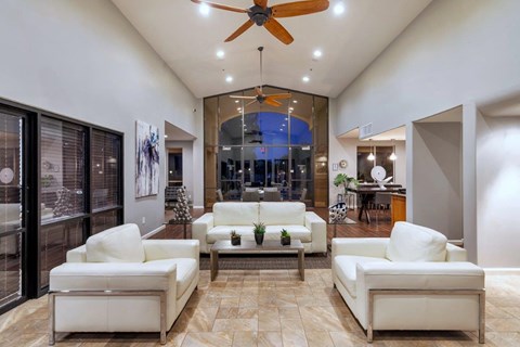 a living room with white furniture and a ceiling fan