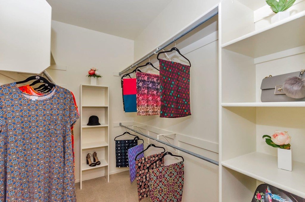 a walk in closet with clothes hanging on racks and shelves