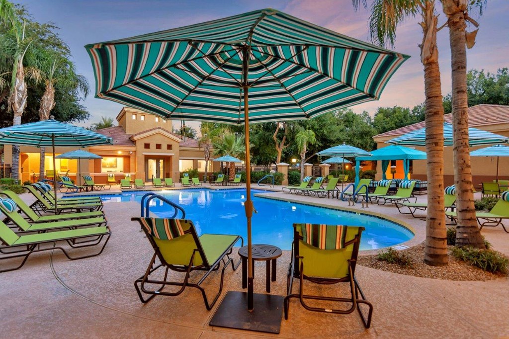 the swimming pool at the resort with chairs and umbrellas