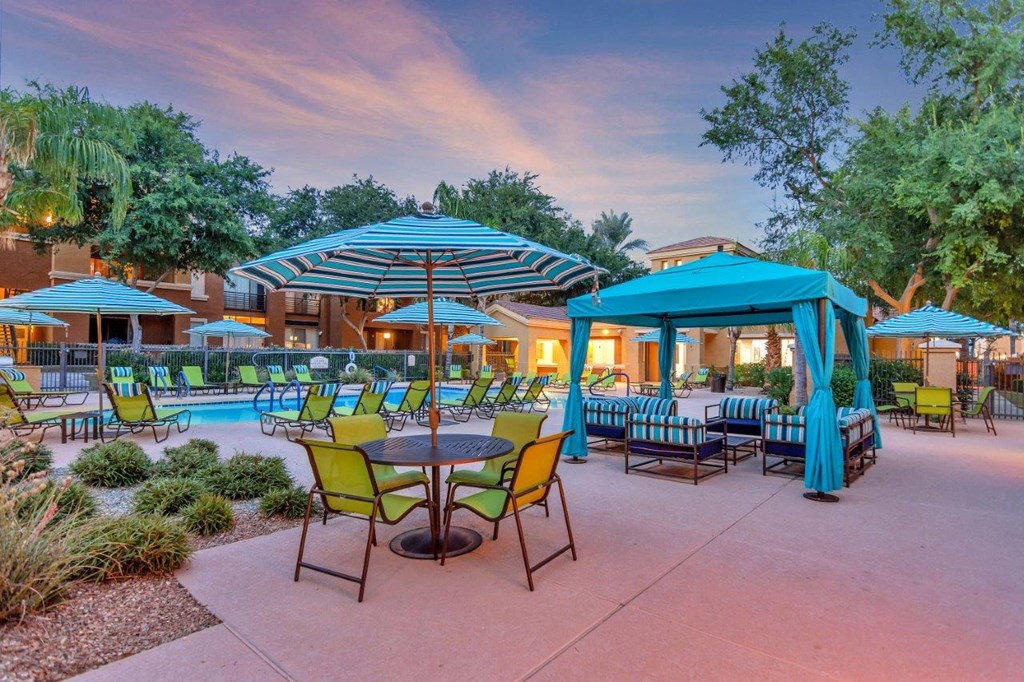 a patio with tables and umbrellas and a swimming pool