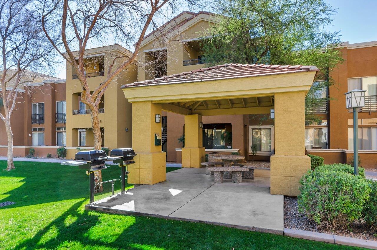 a patio with a grill and a building in the background