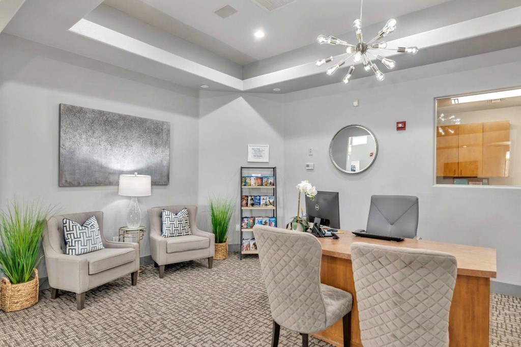 a lobby with a desk and chairs and a mirror