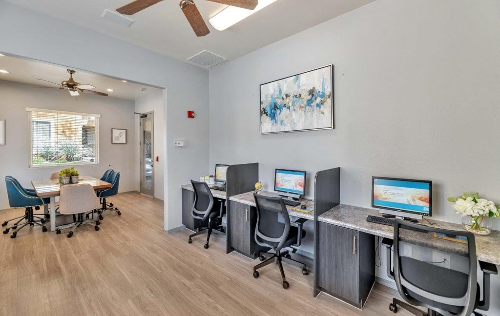 a room with three computers and a table with chairs