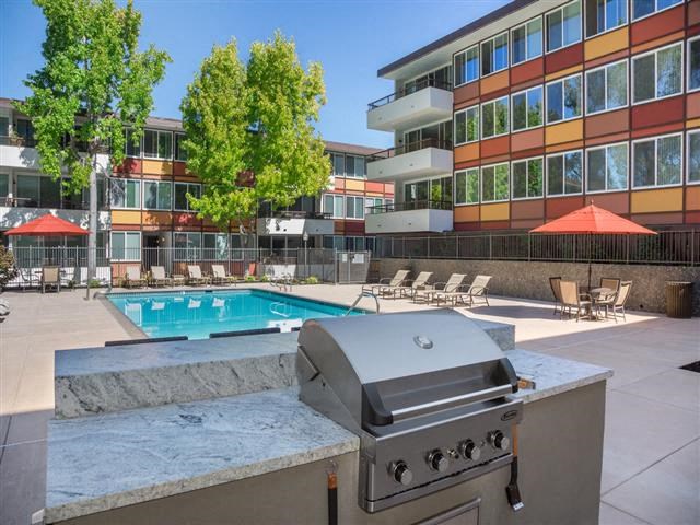 a gas grill on a table in front of a pool