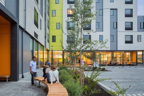 people sitting on a bench outside of an apartment building