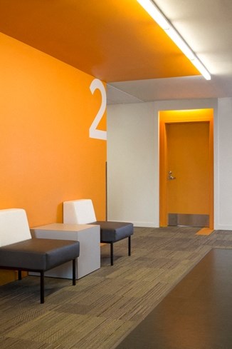 an orange wall with a door and chairs in a waiting room