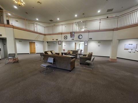 A large room with a carpeted floor and a balcony on the second floor.
