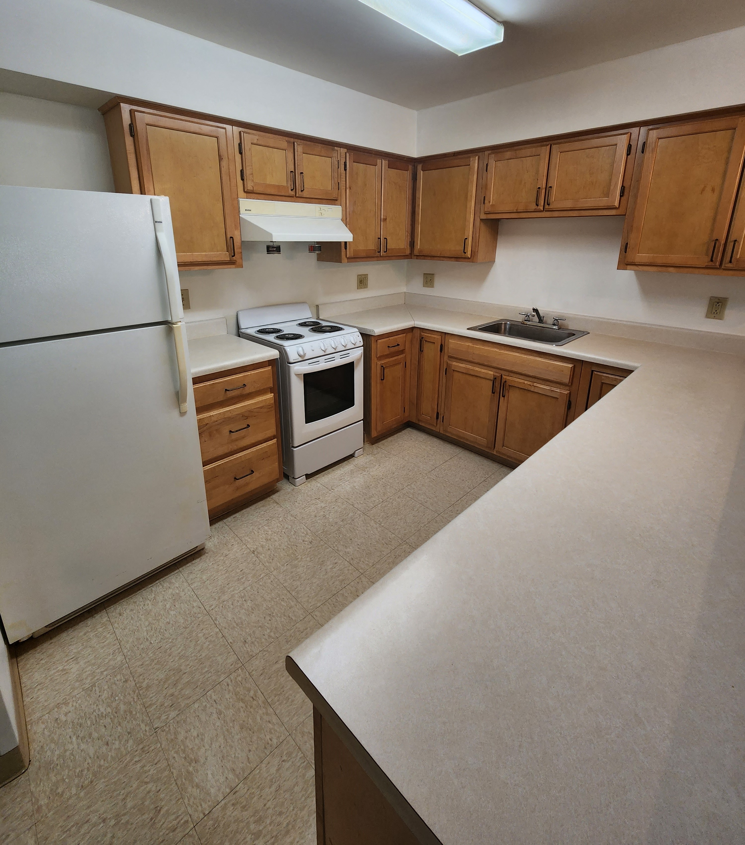A kitchen with white appliances and wooden cabinets.