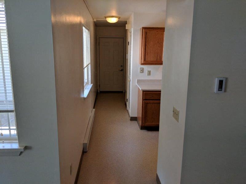 a long hallway with a door to a kitchen