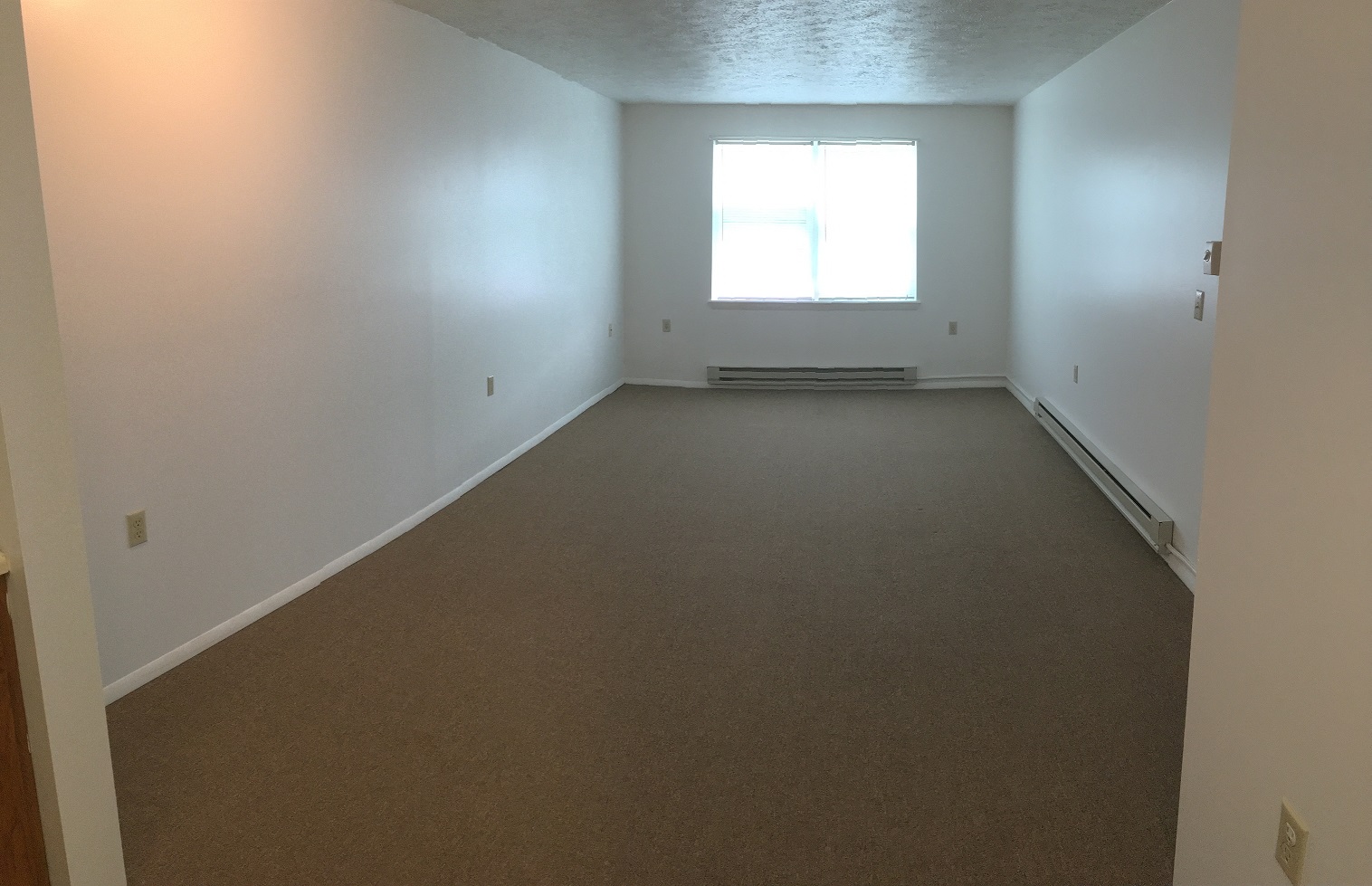 an empty room with a window and white walls